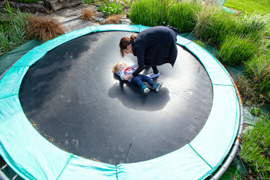 little boy and his mom playing on a trampoline in the country side, Caurel Brittany, France.
