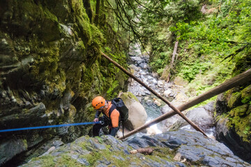 Man rappelling beside waterfall in Frost Creek Canyon.