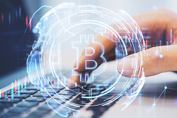 Close up of hands using laptop with glowing bitcoin hologram. Financial technology concept. Double exposure.
