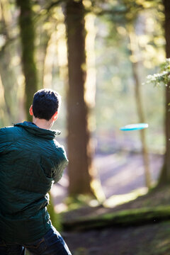Rear view of man throwing frisbee during disk golf game.