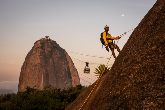 Man rappelling in Morro da Urca with Sugar Loaf Mountain on the back