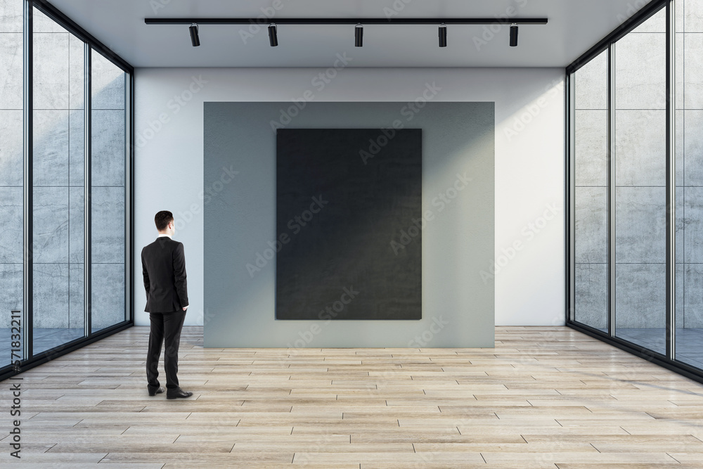 Poster man in black suit back view looking at blank dark poster with space for your logo or text on grey pa