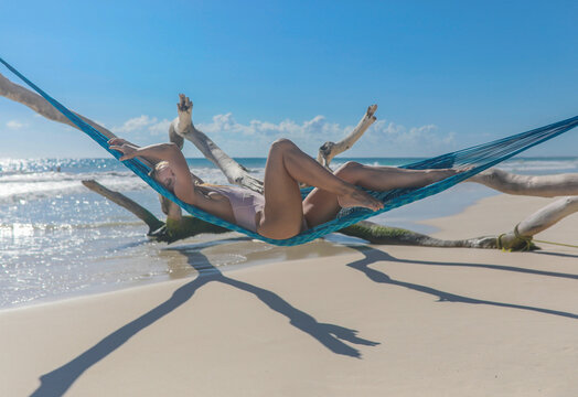 Woman laying on blue hammock on beach