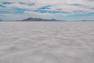 Fototapeta na wymiar Scenic view of Bonneville Salt Flats in western Utah with Silver Island Mountains peaks in the background, Wendover, USA, America. Densely packed salt pan and natural landscape near Salt Lake City