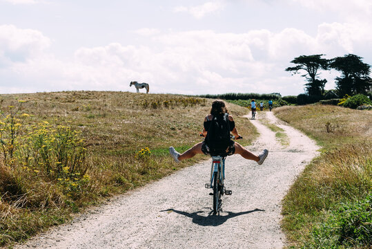 Pretty young woman riding bicycle with open legs in a country road