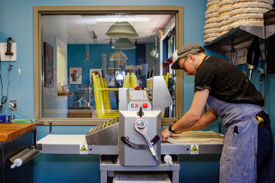 A professional baker prepares to fun a sheet of dough through machine