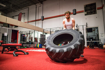 Strong man flipping large tire at the gym.