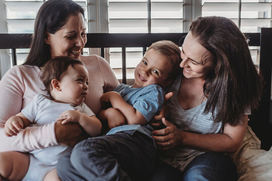 Family With Two Moms Laughing And Cuddling At Home