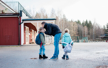 father kissing his kids goodbye at the school gates