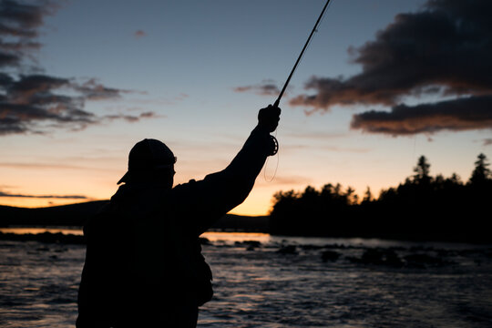 A fly fisherman fishing into the evening on a lake in Maine