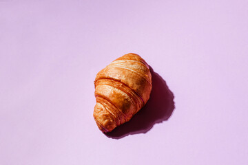 Freshly baked crispy croissant on a pink background. Creative baking banner with space for text. Stylish concept for bakery, coffee and desserts. Aromatic pastries for breakfast