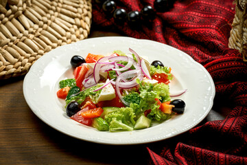 Greek salad with olives and feta cheese in a white plate.