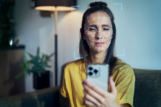 Young woman using phone with face recognition