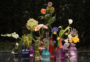still life arrangement of colorful flowers in glass vases in Spring