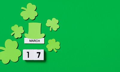 St. Patrick's Day background. Wooden calendar with shamrocks and leprechaun hat on green...