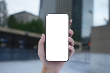 CU 20s Caucasian female holding a phone in a left hand, city downtown in the bg