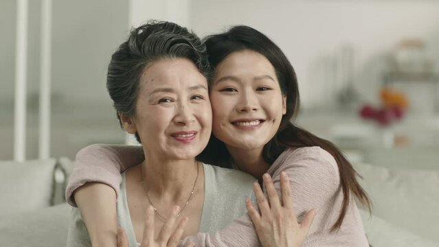 asian senior mother and adult daughter looking at camera smiling