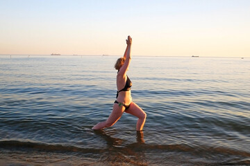 Fototapeta na wymiar woman doing yoga performing asanas and enjoying life on the beach sea, sunset time