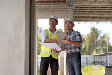 Fototapeta premium Two young Asian engineer visit the construction site, consult and work on site.