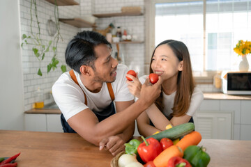Happy Asian couple preparing food to cook breakfast in the kitchen And have fun cooking.