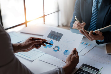 Meeting of business people pointing at graphs and charts to analyze market data, balance sheet, account, net profit, to formulate new sales strategy to increase productivity using laptop computer.