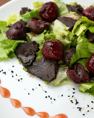 Salad with beets. Boiled beets, liver, lettuce, herbs and sauce. Dish on white plate. Healthy diet. Low calorie food. View from above. Close-up. Soft focus. 