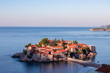 Panoramic view of idyllic island Sveti Stefan after sunrise in Bay of Budva, Adriatic Mediterranean Sea, Montenegro, Europe. Summer vacation in exclusive luxury hotel complex resort at the seaside