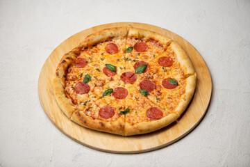 Pizza pepperoni. Pizza with cheese, pepperoni and basil on wooden board on white background. Italian cuisine. Fast food. Close-up. Top view. Copy space.
