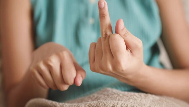 Middle Finger crank gesture and laughing. Young skinny brown woman blue shirt.