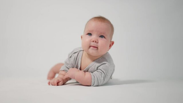 Portrait of a baby. A baby lying on his stomach in close-up against a white background, looking at the cameraman
