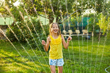 Happy kid girl playing with garden sprinkler run and jump, summer - obrazy, fototapety, plakaty