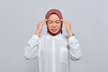 Young Asian Muslim woman pressing finger to temple, having headache, feeling depressed after work isolated over white background