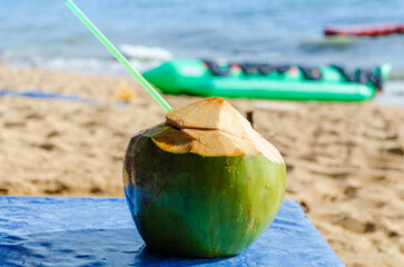 Ready-to-drink coconut fresh green coconut against the backdrop of the sea sandy shore