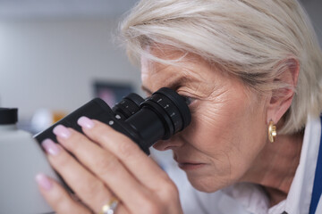 Doctor, microscope and senior woman in laboratory for research, experiment or innovation. Science, biotechnology and elderly female scientist with medical equipment for sample analysis or testing.