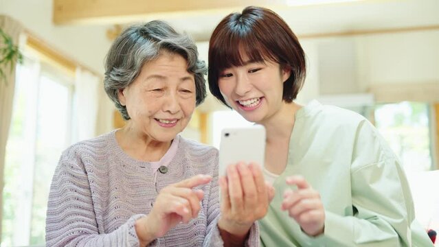 孫にスマートフォンの使い方を教わるシニア女性
