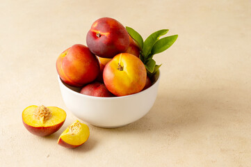Whole nectarine peaches, fresh red fruits in a bowl. Neutral background.