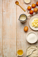 Baking process food ingredients, eggs, flour, butter, oil and milk. Top view, rustic wooden background.