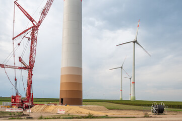 Construction site of a wind turbine, crane next to the tower of the wind turbine, completed wind...