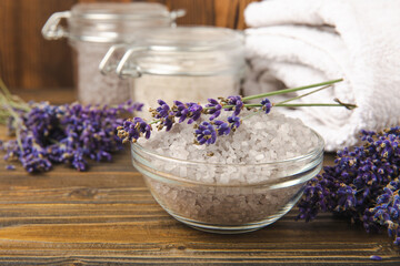 Obraz na płótnie Canvas Sea salt with lavender flowers in a bowl on a brown textural background. Bath salt with lavender extract and aroma. Beauty spa treatments. Skin care concept.