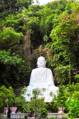 white marble buddha sculpture in a tropical garden