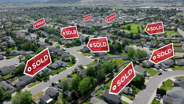 Drone shot of SOLD signs popping up across residential houses.
