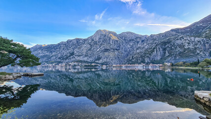 Naklejka na ściany i meble Panoramic view of bay of Kotor on sunny summer day at Adriatic Mediterranean Sea, Montenegro, Balkans, Europe. Fjord winding along coastal towns. Lovcen mountains are reflected in the water surface