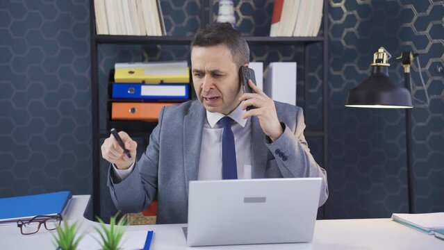 hile talking about work problems on the phone in the office, he gets angry and cannot control his anger.
Office worker man hears on the phone that he is in trouble with something and shouts in anger, 