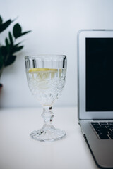 glass of water and laptop on white desk 