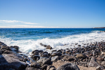 Fototapeta na wymiar Crushing waves of the ocean at the canarian pebble beach.