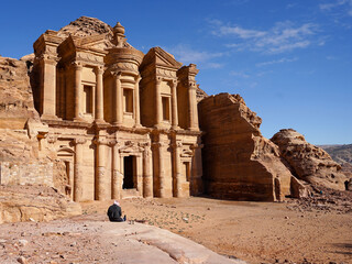 Bedouin sitting next to Petra Ad Deir Monastery, famous carved temple in Petra historic city, Jordan