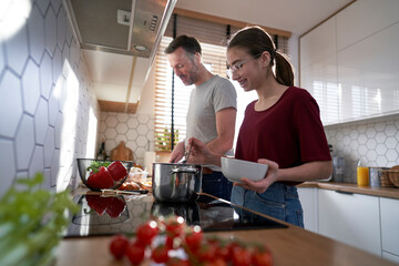 Caucasian man cooking with teenager daughter at home