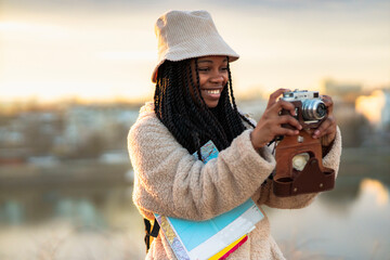 Tourist african american woman with camera taking photos of beautiful location, she's happy and...