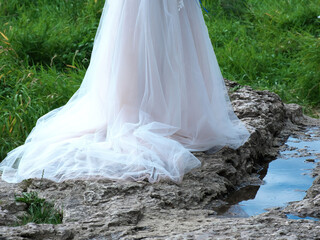 White dress of the bride. The dress lies on the stone bank of the river.