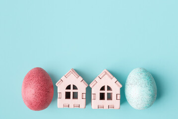 Painted Easter eggs and wooden houses on blue background with copy space. Easter holiday greeting concept - 571872079